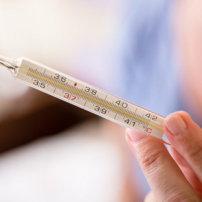 Hand holding analog medical thermometer